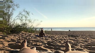Un'esibizionista pubblica mostra il suo pene su una spiaggia nuda, si eccita.